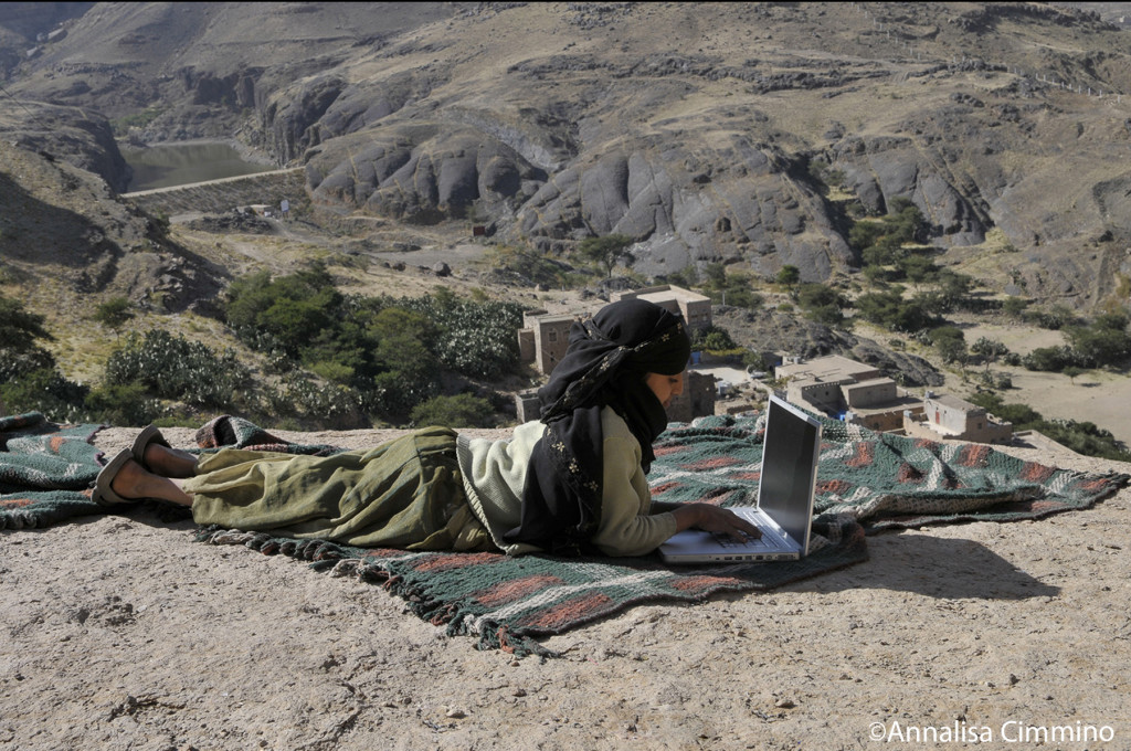 Yemen, kid surfing in internet on top of a mountain of the BaytBaws Village